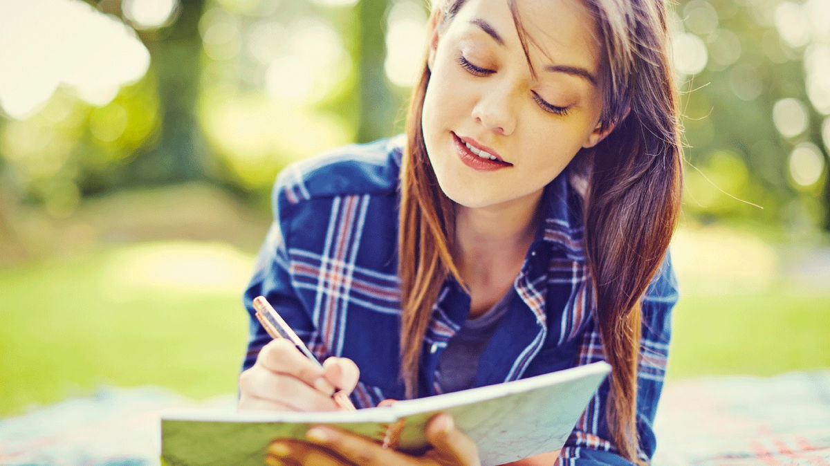 ragazza che scrive su diario al parco