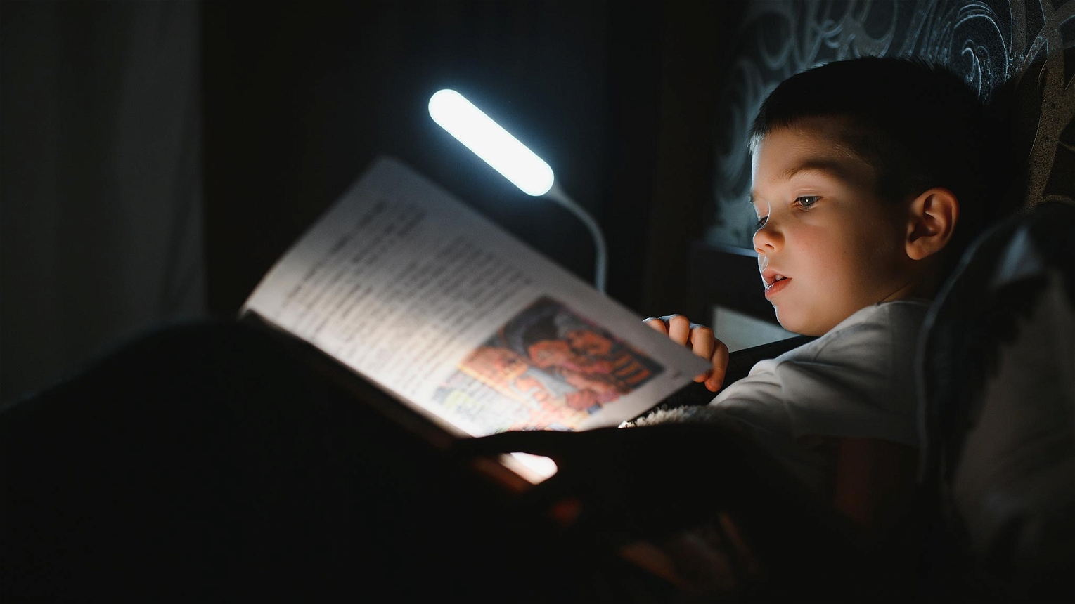 luce da lettura che illumina libro bambino a letto
