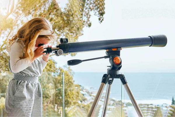 bambina che usa telescopio al mare