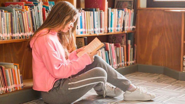 ragazza legge libro seduta in terra