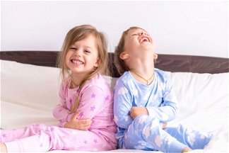 due bambini in pigiama sul letto