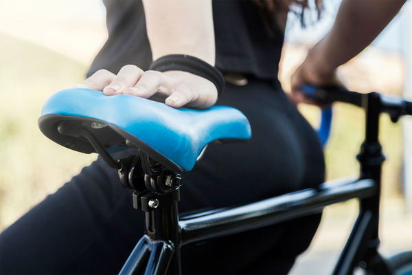 ragazza appoggiata alla bicicletta con la mano sul sellino