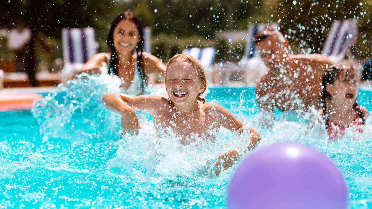 genitori che giocano a palla con bambino in piscina