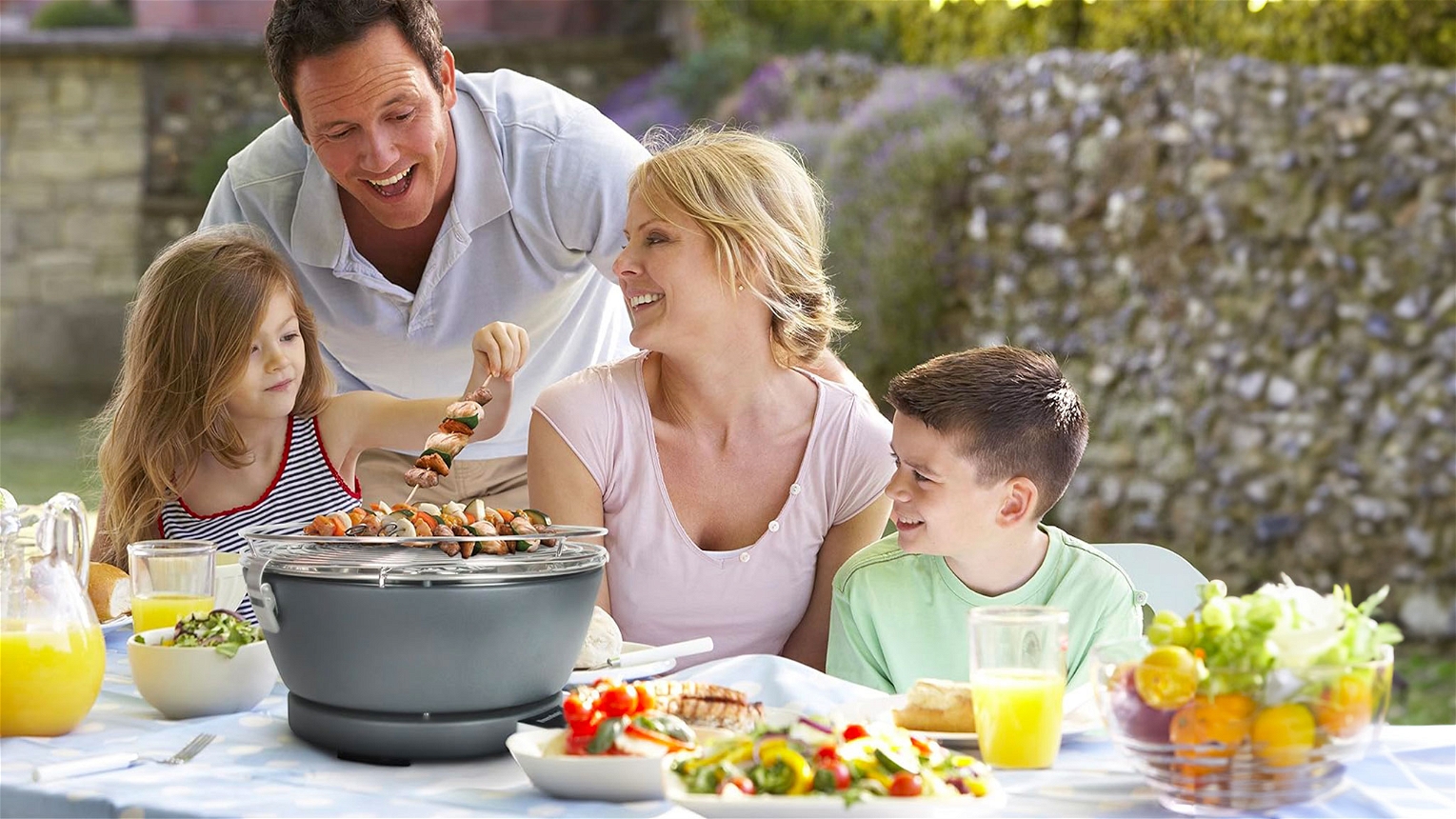 Famiglia felice di grigliate sul tavolo con il grill da tavolo