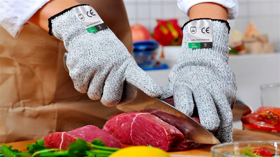 uomo che indossa guanti antitaglio in cucina