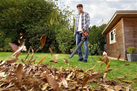 uomo che soffia le foglie con il soffione per pulire il giardino