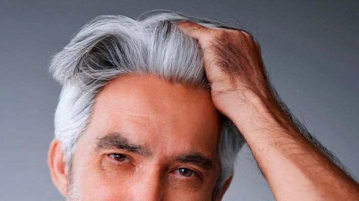 uomo 40 anni che si tocca capelli bianchi