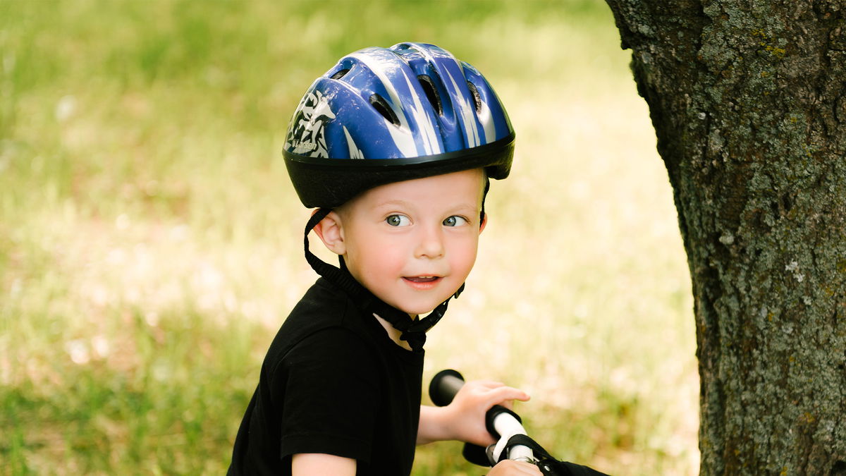 Bambino in bici con casco