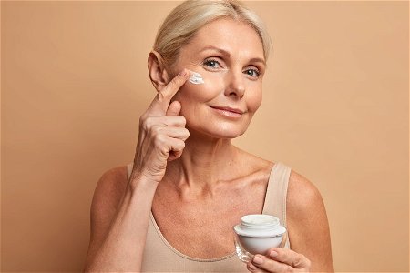 donna che si applica una crema al collagene sul viso