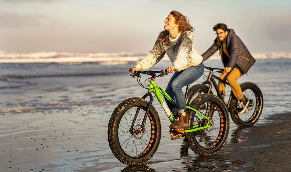 Uomo e donna su deu fat bike lungo il bagnasciuga