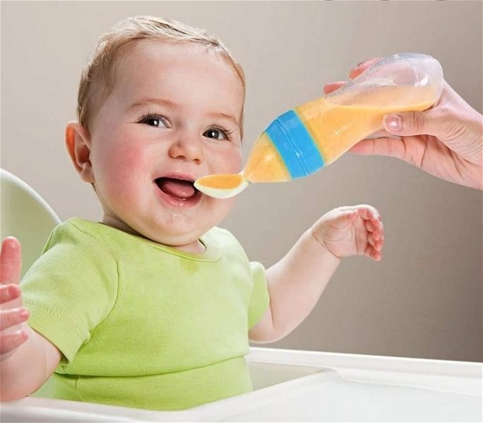 neonato che mangia da un biberon con cucchiaino