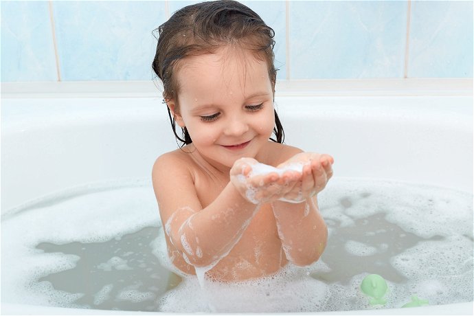 Bambina che fa il bagno nella vasca con la schiuma