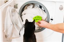 gatto nero che guarda la lavatrice aperta con cattura peli dentro