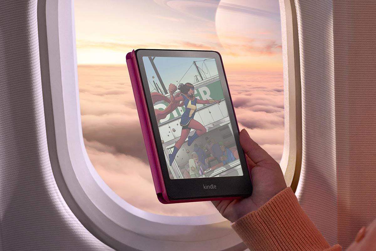 Kindle Colorsoft in una mano davanti l'oblò si un aereo 