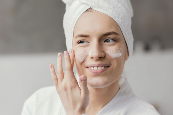 Ragazza che si applica la crema viso