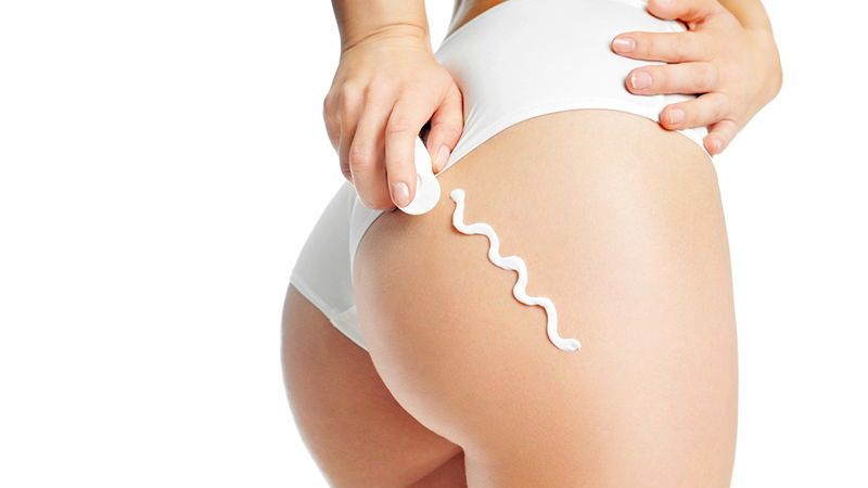 Donna con gluteo in primo piano che applica la crema