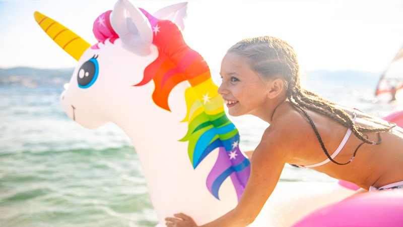 bambina su gonfiabile a forma di unicorno al mare