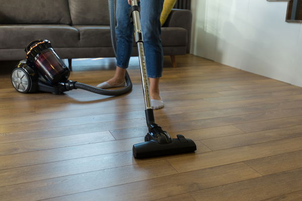 Donna che passa l' Aspirapolvere senza sacchetto sul parquet