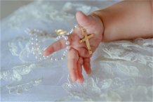 manina di bambino che tiene un rosario