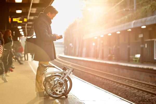 uomo alla stazione con bici pieghevole