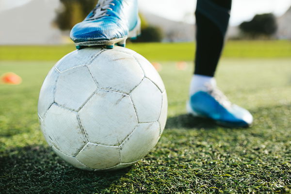 Piedi di calciatore con un pallone sul campo