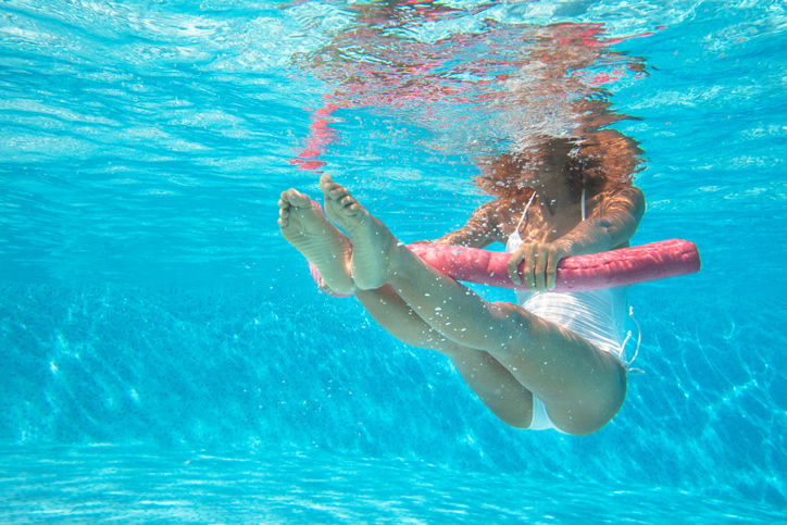 ragazza con tubo rosa galleggiante in piscina