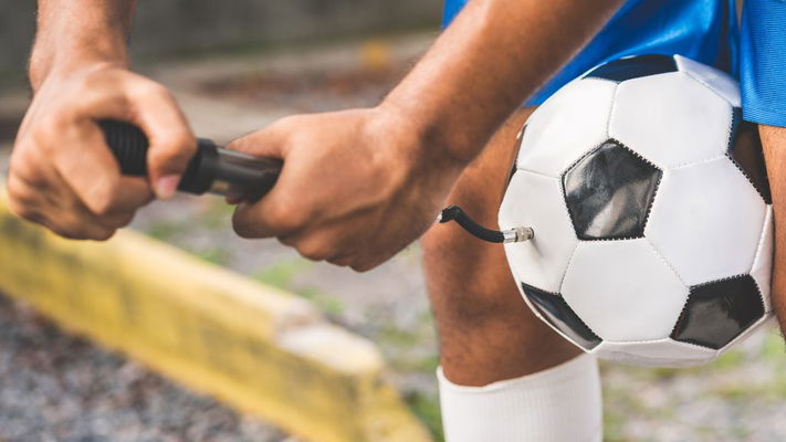 giocatore che gonfia pallone da calcio