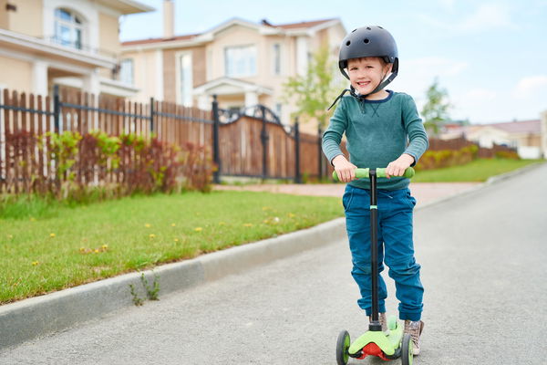 bambino che va su monopattino a tre ruote 