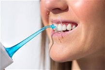 donna che si pulisce i denti con idropulsore