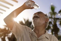 uomo anziano che si versa acqua sulla fronte