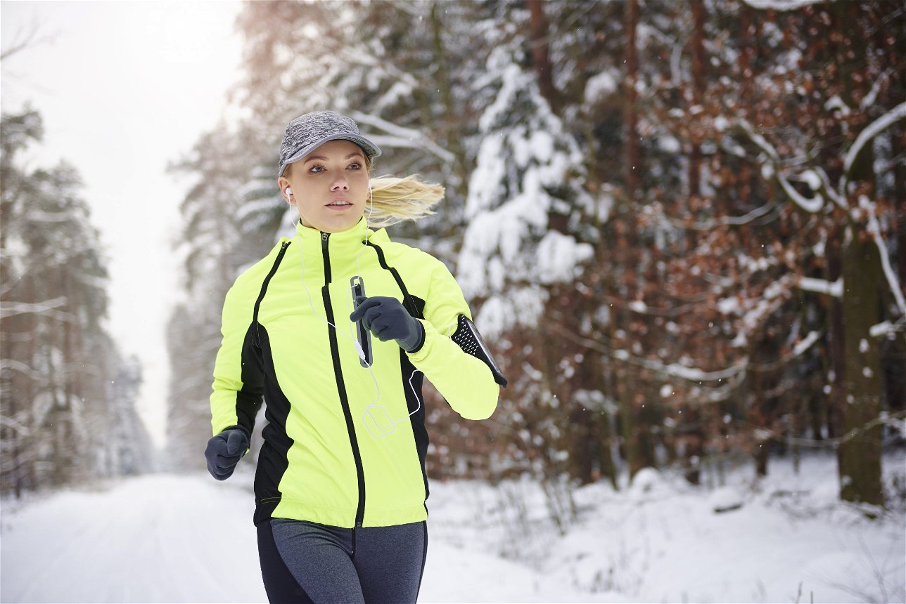 donna che corre con maglia termica nella neve