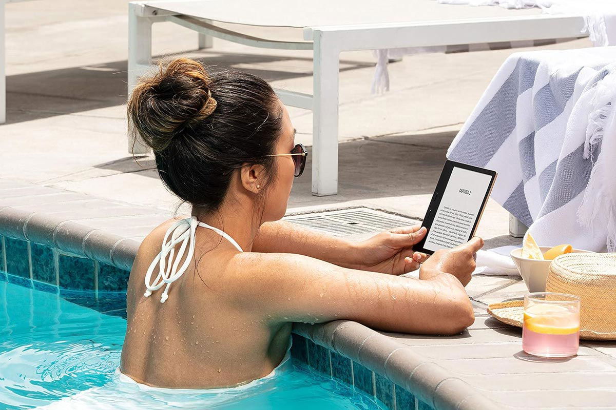 Ragazza a bordo piscina che legge su Kindle Oasis