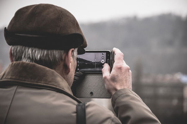 anziano con smartphone mentre fa una foto