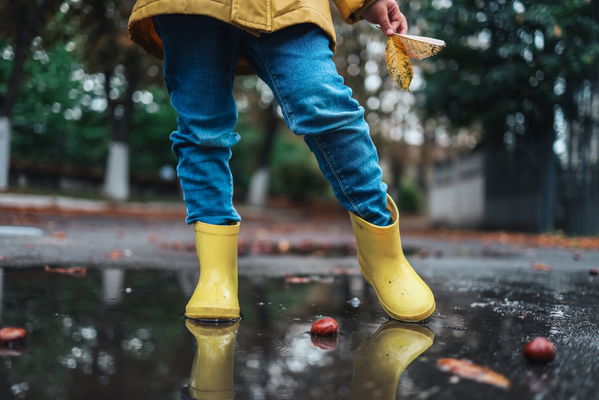 bambino con stivali in pozza