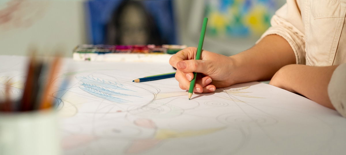 Mani di bambino che disegnano su foglio bianco